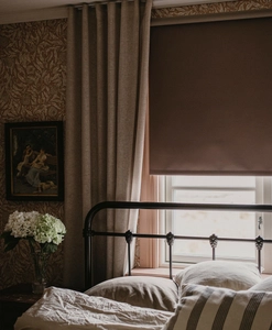 Mörkläggande brun rullgardin med beige gardinlängd i sovrum