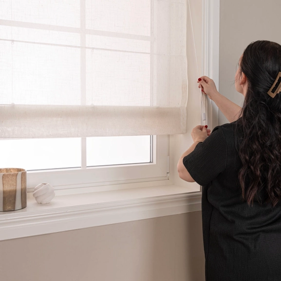 Hissgardin med kvinna som justerar gardinen med en lina