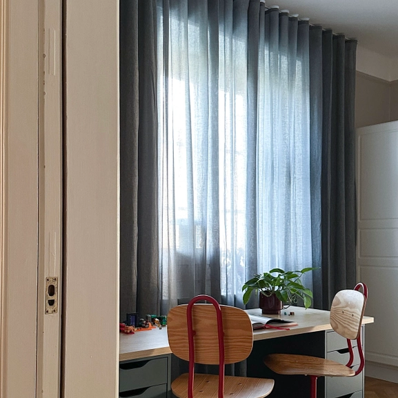 Blå gardin framför skrivbord med retrostolar