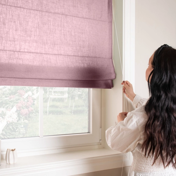 Kvinna justerar dovlila hissgardin med lina