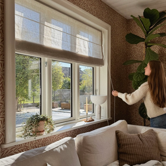 Kvinna justerar en beige hissgardin