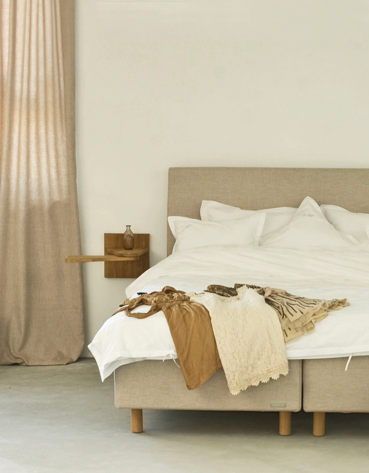 Sängben i trä på en beige säng i lantligt sovrum