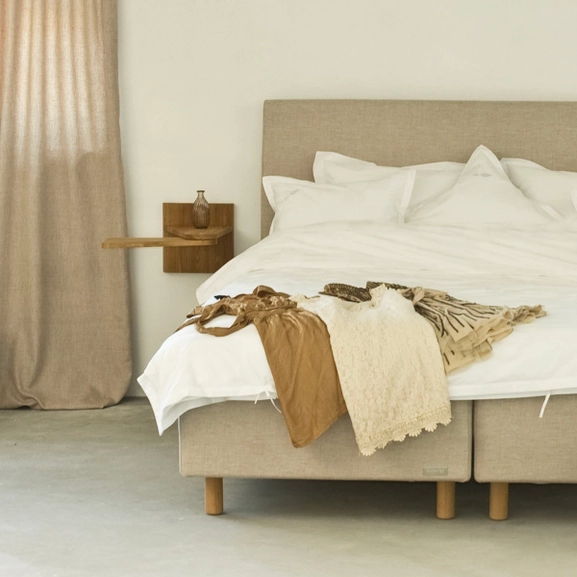 Sängben i trä på en beige säng i lantligt sovrum