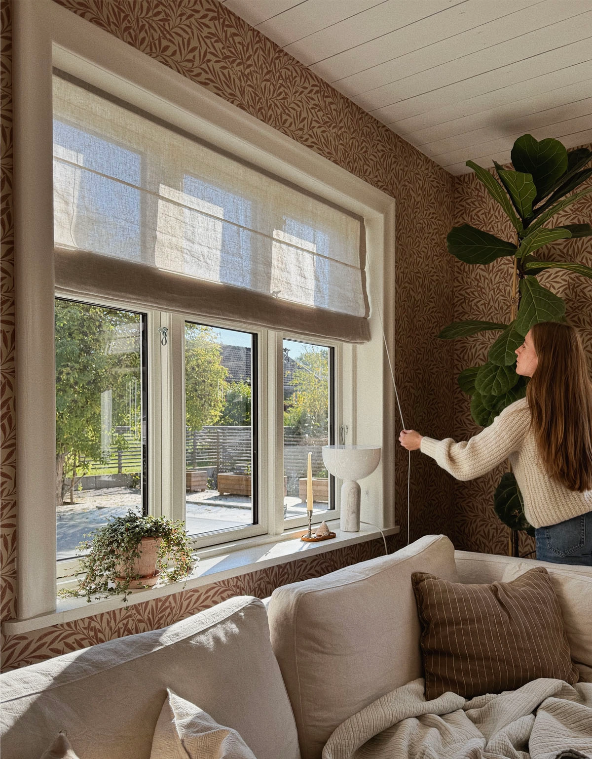 Kvinna justerar en beige hissgardin