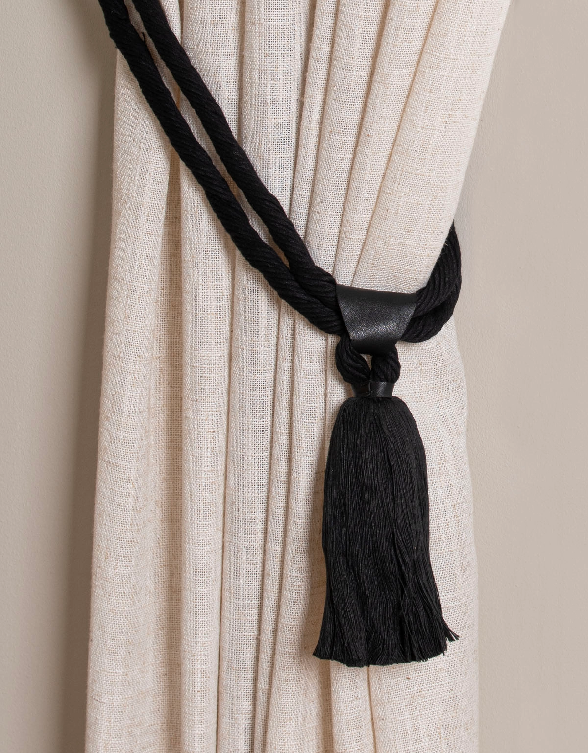 Svart gardinomtag med tofs och detalj i läder
