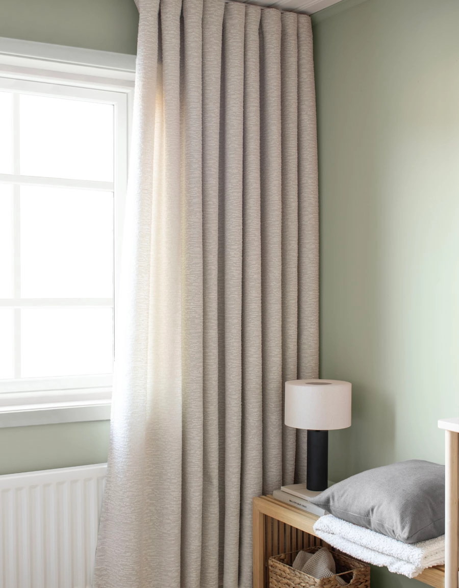 Grå bouclégardin i grönt rum