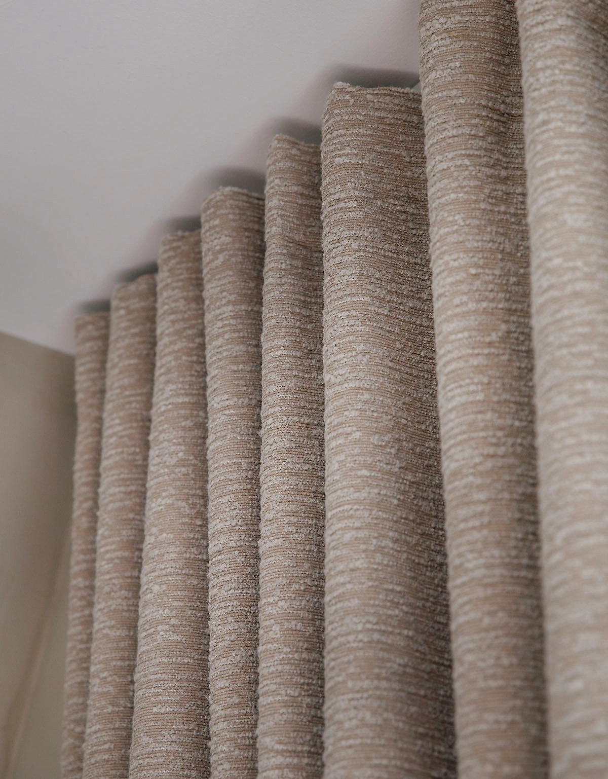 Närbild på vågorna på en bouclégardin i beige nyans