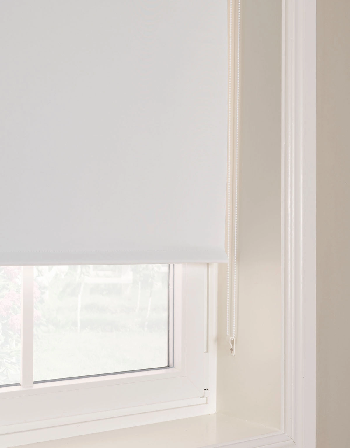 Närbild på vit mörkläggande rullgardin med kulkedja