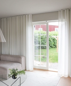 Vita skira gardiner i ett vardagsrum framför altandörr