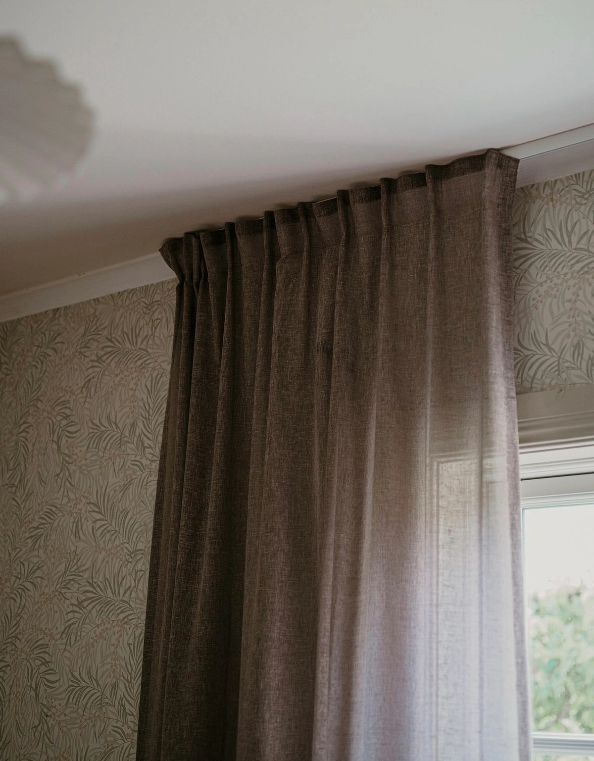 Brun gardin upphängd med fingerkrokar på skena