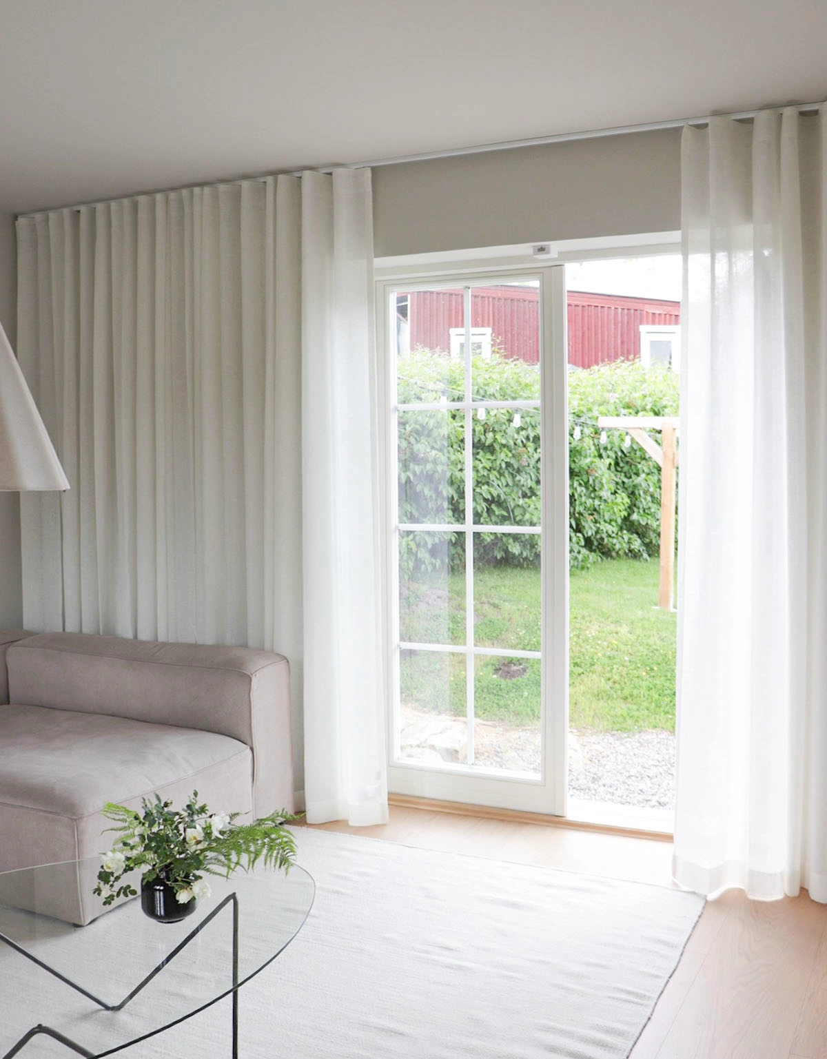 Vita skira gardiner i ett vardagsrum framför altandörr