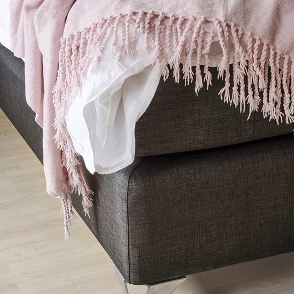 Sängben i borstat stål på en mörkgrå kontinentalsäng