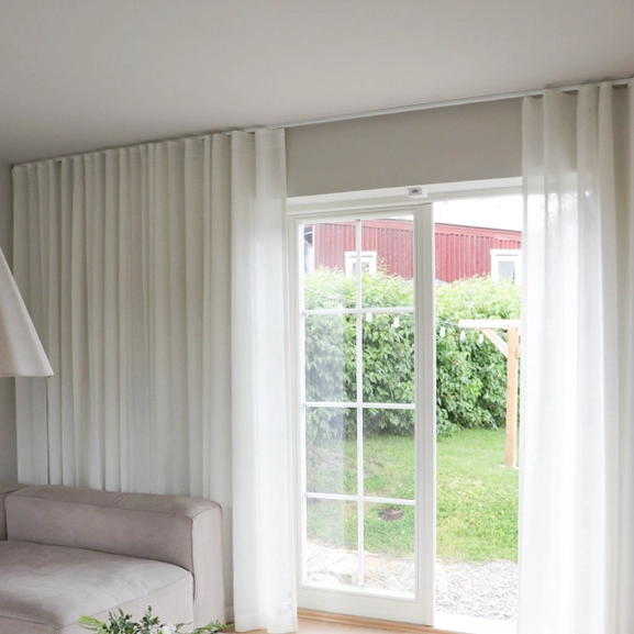 Vita skira gardiner i ett vardagsrum framför altandörr