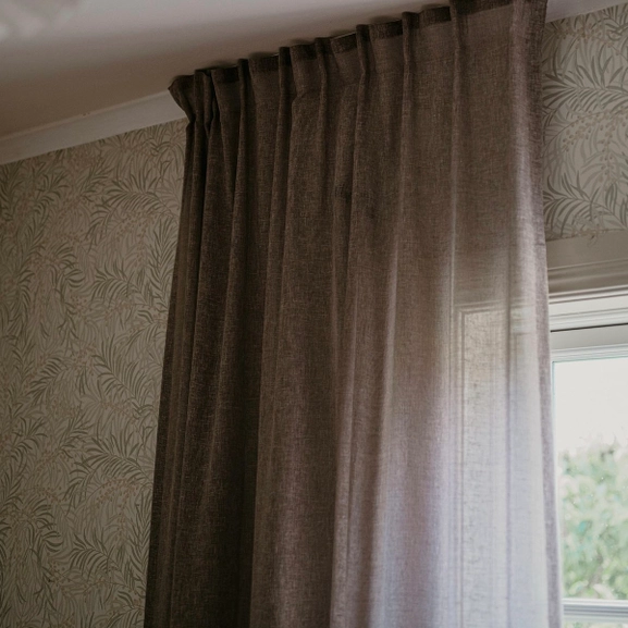 Brun gardin upphängd med fingerkrokar på skena