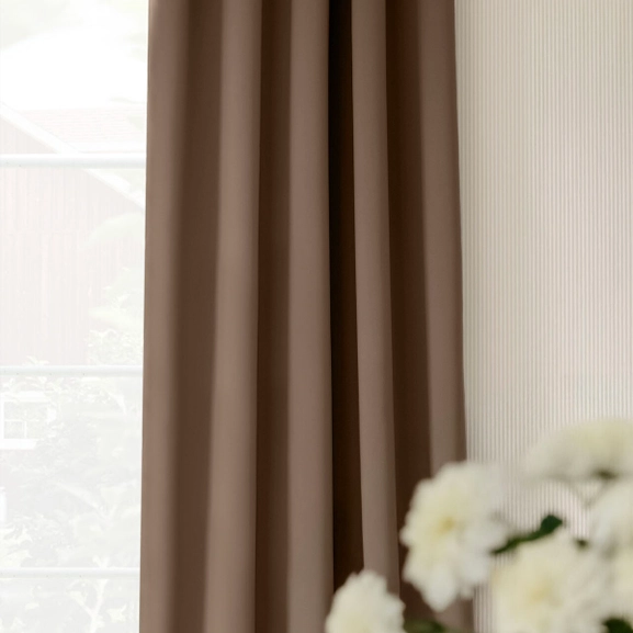 Brun mörkläggningsgardin på gardinstång