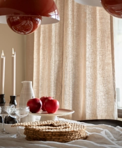 Beige gardin i bakgrunden av ett dukat julbord.