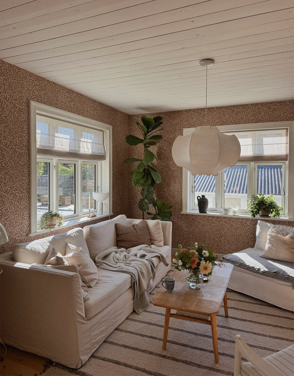 Beige hissgardin i vardagsrum med mönstrade tapeter