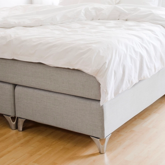 Sängben i stål på ljusgrå säng