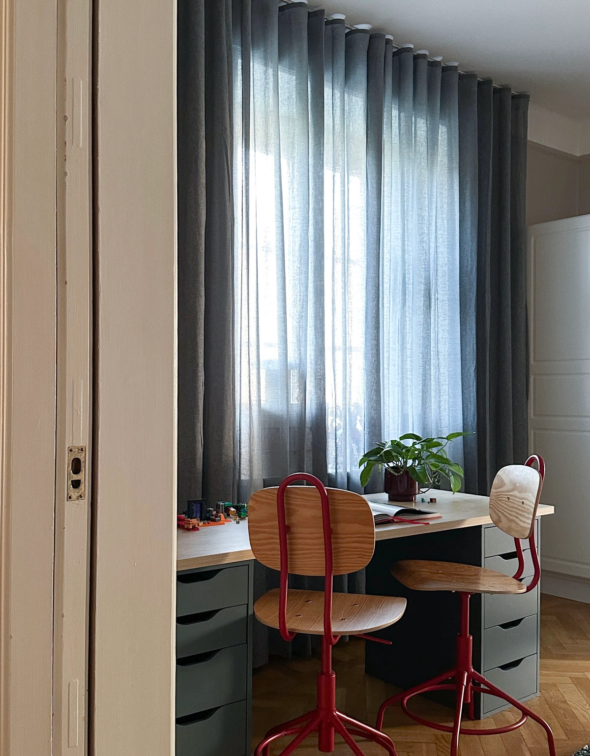 Blå gardin framför skrivbord med retrostolar